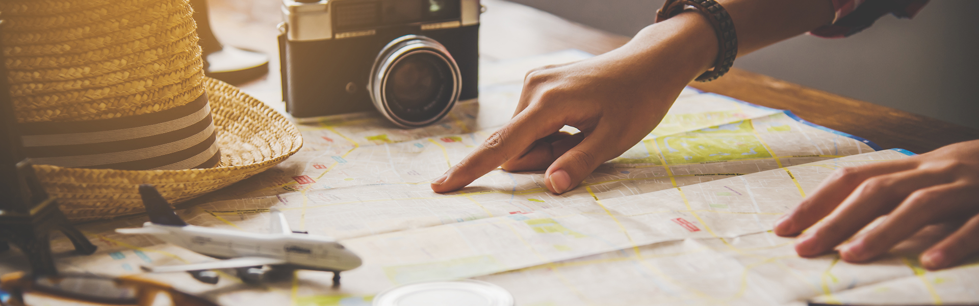 Traveler planning a trip with a paper map, camera, and travel accessories on a table