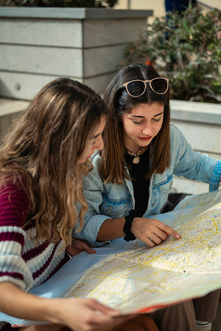 Two travelers poring over a paper map, planning their next trip together